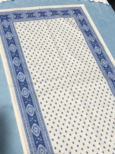 Load image into Gallery viewer, Acrylic coating allows for universal wipe clean finish, allowing for liquids and oils to bead off. Measures 16.5 by 60 in. Pictured on a 72 inch length table for reference, but may be draped over the sides of a smaller table as well. Manufactured by l'Ensoillade and made in France. Pictured in ecru ciel.
