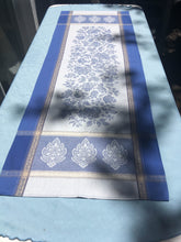 Load image into Gallery viewer, Universal wipe clean finish allows for liquids and oils to bead off. Measures 20.5 by 58 in. Pictured on a 72 inch length table for reference, but may be draped over the sides of a smaller table as well. Pictured in deep oceanic caprice blue with dark blue and washed out denim at intersecting floral garland borders featuring jacquard woven pomegranate-like baroque floral blooms and beautifully detailed leaves and bouquets of intertwined branching elaborated fleur de lys.