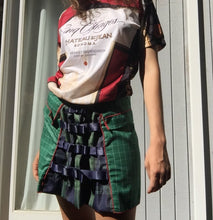 Load image into Gallery viewer, dirndle back multi navy satin bow ruched plaid taffeta upcycled chruistmas napkin waist cuffed pleat flounce school uniform skirt great for holiday winter parties or camp cosplay fashion. Upcycled Christmas nakins are a grid of dark evergreen with bright red woven edges.