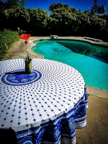 Repeating abstract pattern of flora inspired diamonds with tablecloth borders introducing a leafy paisley design. White with blue and black accent colors. Measures 68 inches diameter. Acrylic finish. Made in France.