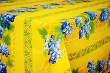 Load image into Gallery viewer, This acrylic coated cotton rectangular yellow tablecloth measuring 96 inches in length celebrates vineyards and spring, with a beautiful motif of provincial blue grape clusters and leaves. Le Cluny, made in France. Easy care wipe clean finish.
