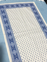 Load image into Gallery viewer, Acrylic coating allows for universal wipe clean finish, allowing for liquids and oils to bead off. Measures 16.5 by 60 in. Pictured on a 72 inch length table for reference, but may be draped over the sides of a smaller table as well. Manufactured by l&#39;Ensoillade and made in France. Pictured in ecru ciel.
