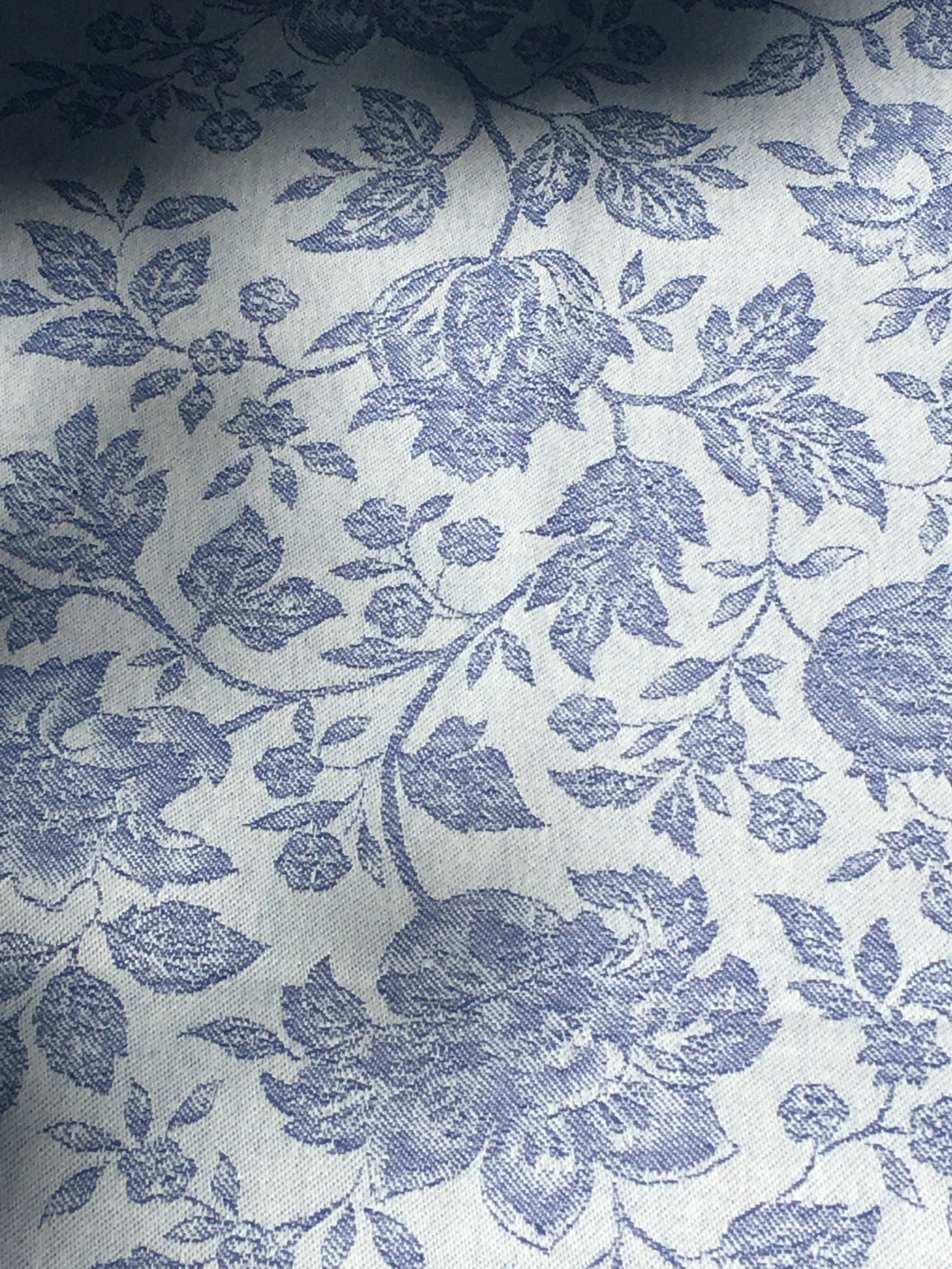 Anti-stain teflon treatment allows for liquids to bead off and universal wipe clean finish allows for liquids and oils to bead off. Measures 20.5 by 58 in. Pictured on a 72 inch length table for reference, but may be draped over the sides of a smaller table as well. Pictured in caprice blue featuring jacquard woven pomegranate-like baroque floral blooms and beautifully detailed leaves and bouquets of intertwined branching elaborated fleur de lys.